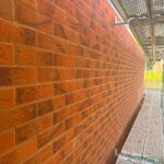 Long red facing brick elevation with straight courses and clean joints, seen from the scaffold on a large housing development