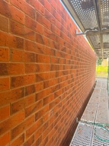 Long red facing brick elevation with straight courses and clean joints, seen from the scaffold on a large housing development